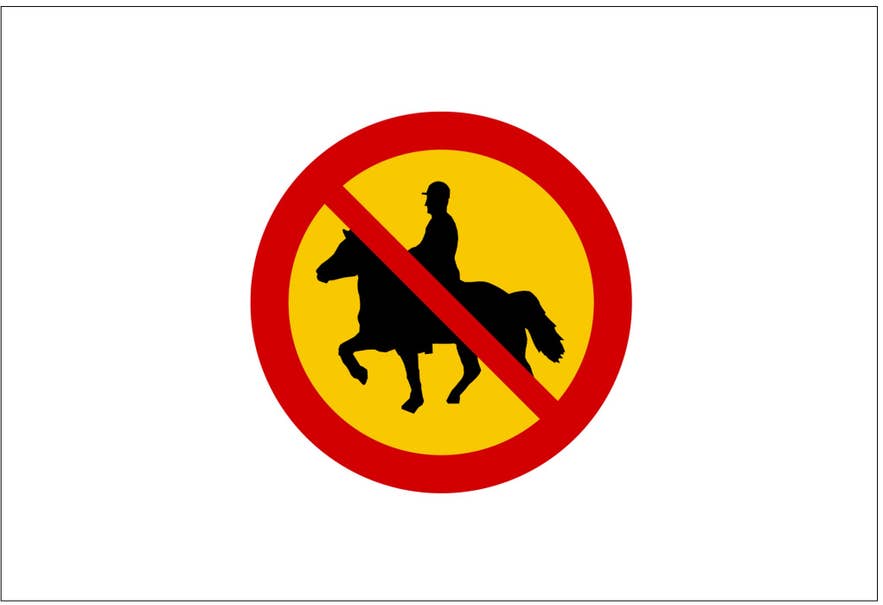 Okrągły, żółty znak drogowy na Islandii z czerwoną obwódką i linią biegnącą przez środek informuje, że jazda konna i jeźdźcy nie są dozwoleni.