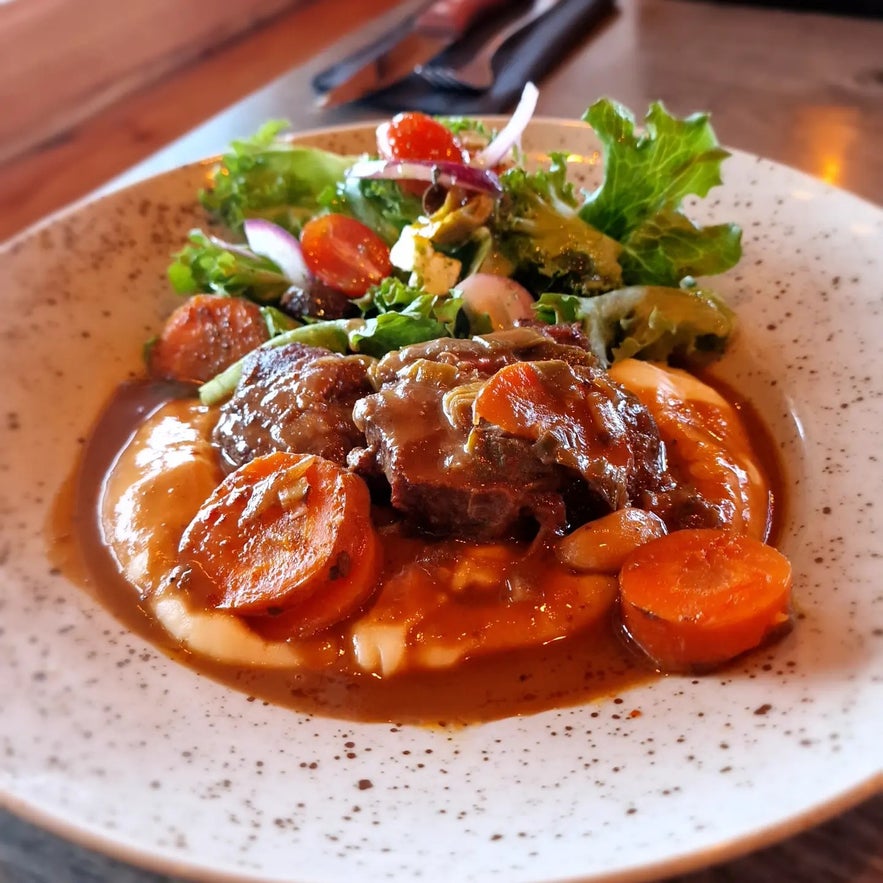 Delicious meat stew with carrots, mashed potatoes, and fresh salad served at Kaffi Hornid restaurant.