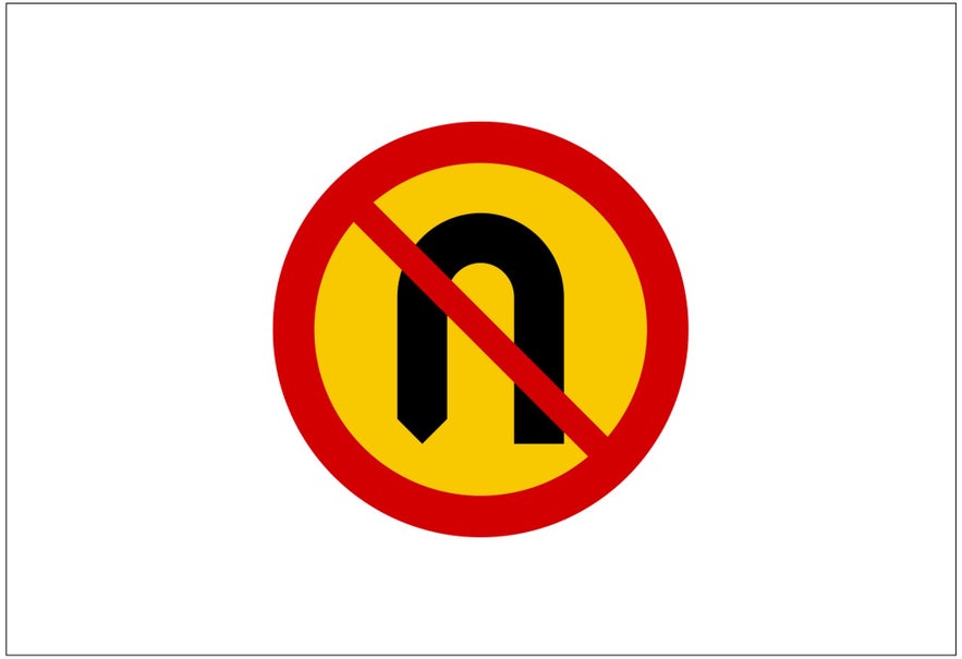 An Icelandic road sign featuring a black U-turn arrow inside a red circle with a diagonal red slash across it indicates that U-turns are not allowed in the area.