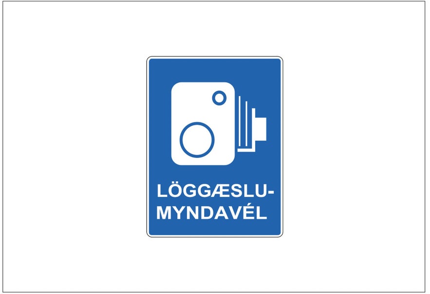 A blue rectangular sign with a white image of a speed camera and Icelandic words informs drivers of a speed enforcement area.