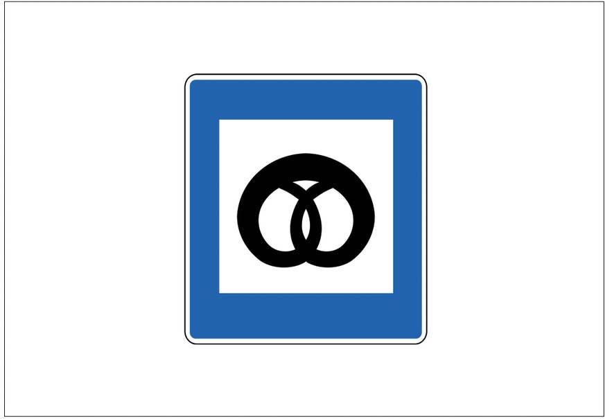 青と白の四角い道路標識に黒いプレッツェルのイラストが描かれており、ベーカリーを示しています。