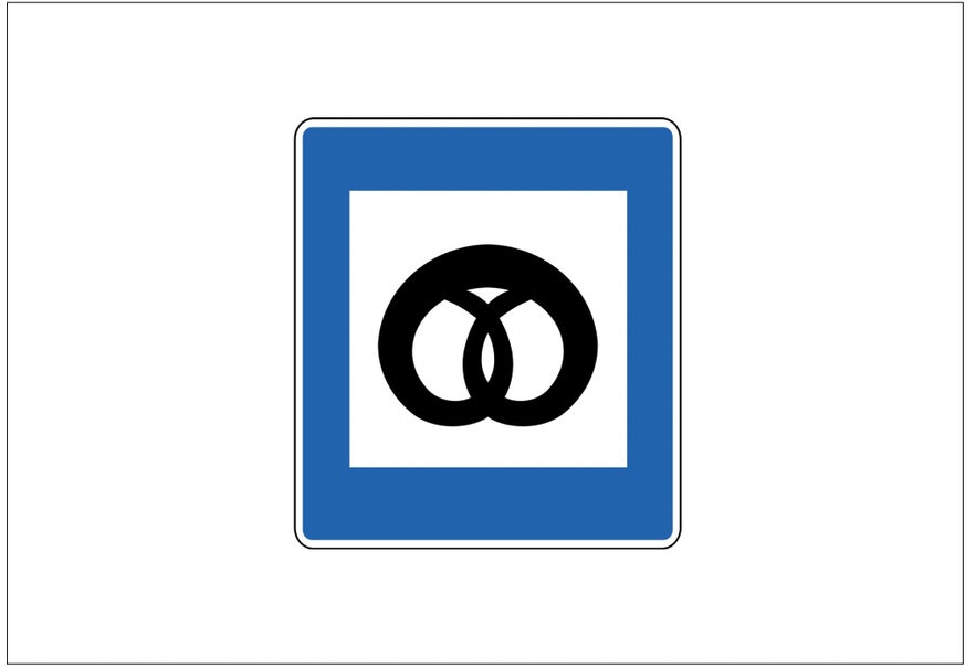 A blue and white square road sign in Iceland with a black image of a pretzel indicates a bakery.