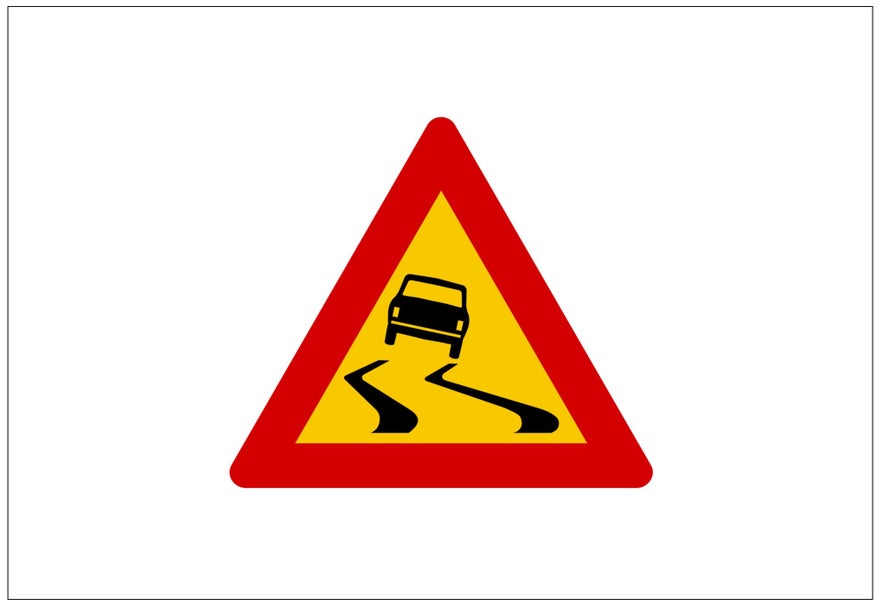 A yellow triangular Icelandic road sign indicates the road is slippery when wet.