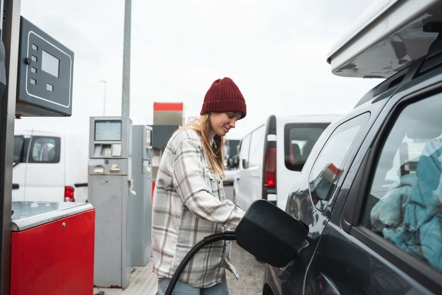 A woman fills her car with fuel at a self-service station during a road trip in Iceland.