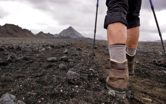 Close-up of hiker’s boots walking on volcanic black sand trail during a hiking trip in Skaftafell Nature Reserve.