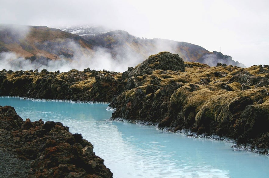 The blue water of the Blue Lagoon contrasting with the lava field and mountains in the background