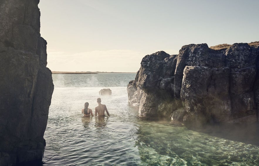 People entering the sky lagoon with cliffs above the water