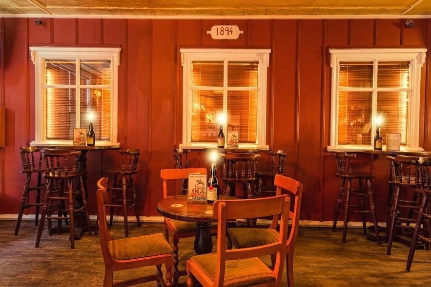 Cozy interior of Den Danske Kro in Reykjavik with wooden furniture and vintage decor under warm lighting.