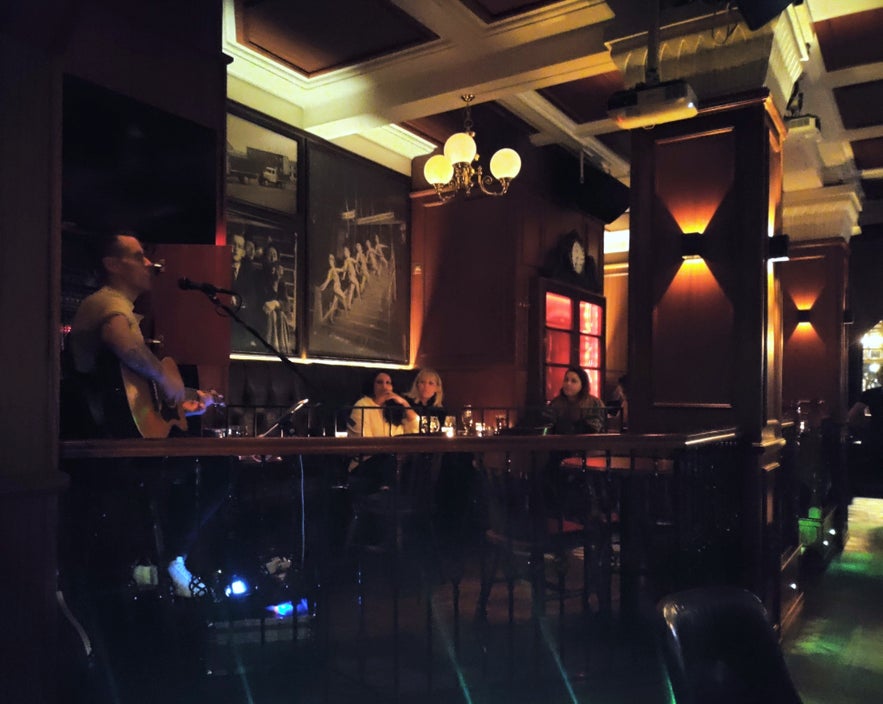 Live music at the English Pub in Reykjavik, with guests seated at candlelit tables and vintage black-and-white photos on the wall.
