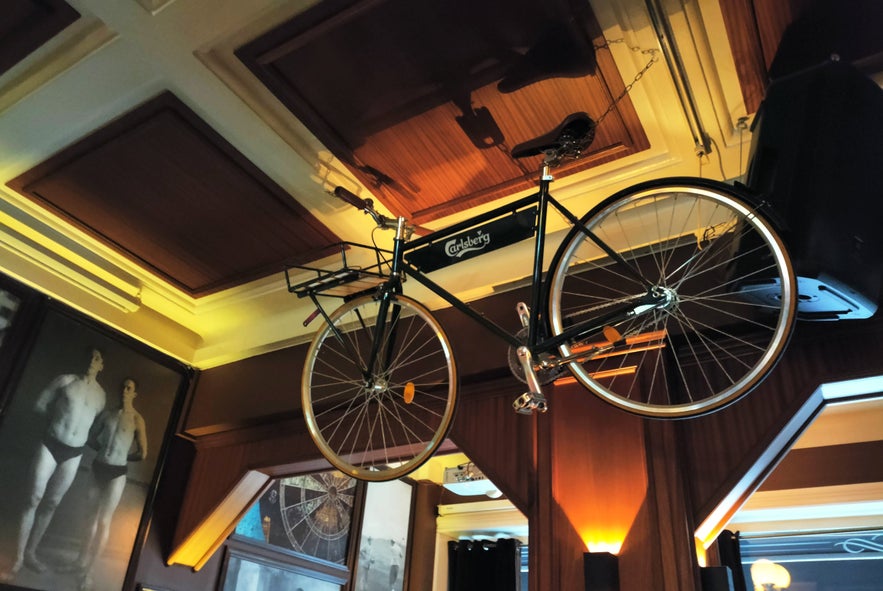 Carlsberg-branded bicycle hanging from the ceiling at The English Pub in Reykjavik, surrounded by vintage décor.