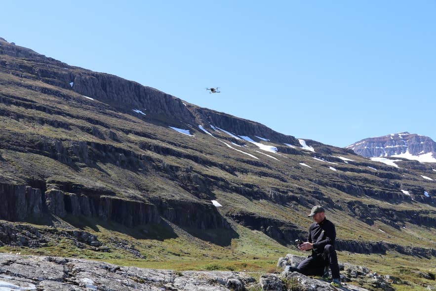 アイスランド東部のセイジスフィヨルズルでドローンを飛ばすパイロット。アイスランドのダイナミックな高地を空撮