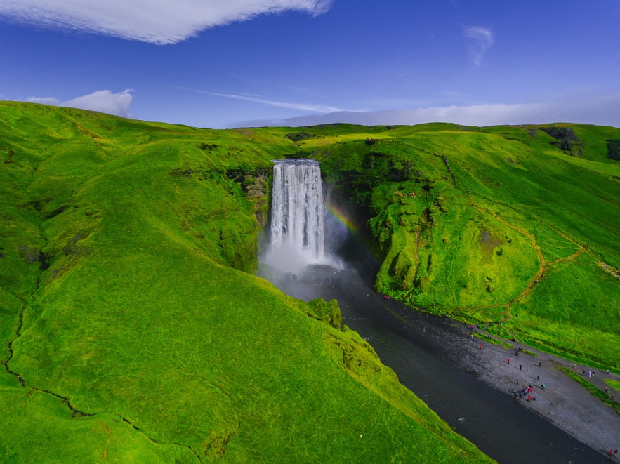 Capturing Skogafoss Waterfall’s dramatic drop and lush green surroundings while flying drones in Iceland.