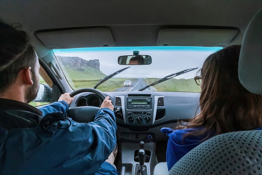 Tourists sharing a rental car for a road trip on the Ring Road, showing cost-effective transportation in Iceland.