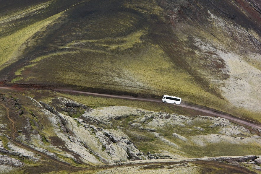 Tour bus driving through Iceland’s Highlands near Landmannalaugar, showcasing rugged off-road transportation in Iceland.