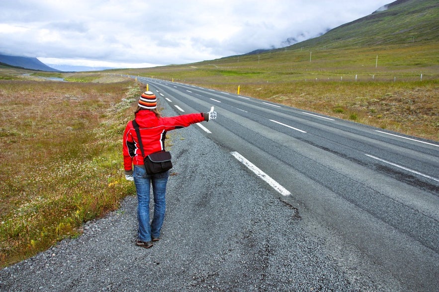 Traveler hitchhiking on the Ring Road, showcasing budget-friendly transportation in Iceland.
