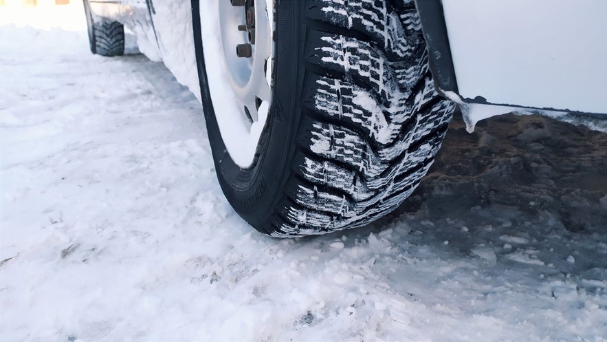 Close-up of a studded winter tire designed for safe driving in Iceland’s snowy and icy conditions.