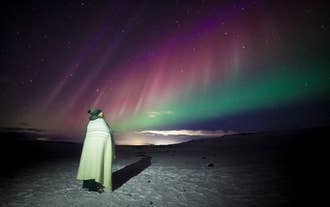 Northern lights in Iceland glowing above a snowy landscape during a winter night.