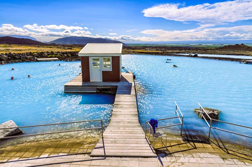 Earth Lagoon au lac Myvatn, dans le nord de l’Islande, avec une eau géothermale bleue et vue sur les montagnes.