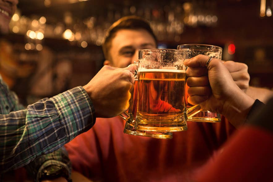 Friends clinking beer mugs during happy hour in Reykjavik, enjoying the city’s lively nightlife.