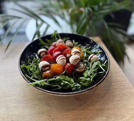 Fresh caprese salad with cherry tomatoes, mozzarella, and arugula served at Ice Cave Bistro in Vik, Iceland.