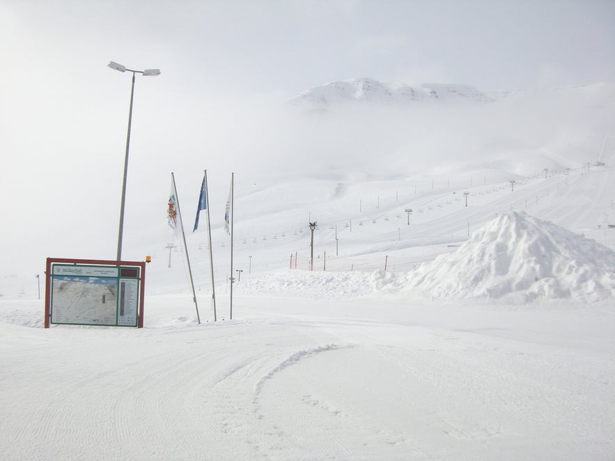 Skiing and snowboarding in Iceland at Hlidarfjall Ski Resort in Akureyri with snowy slopes and ski lifts in view.