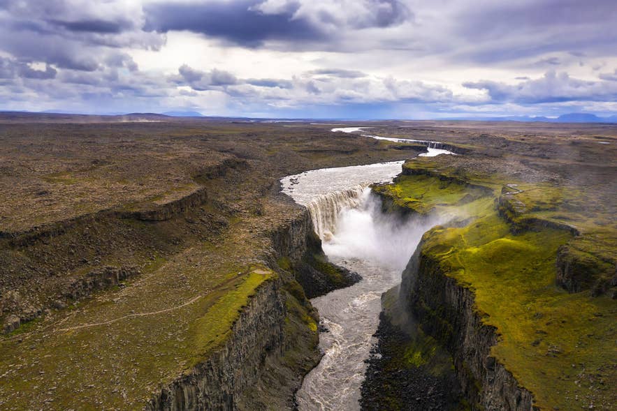 Aerial view of Jokulsargljufur canyon in north Iceland, with Dettifoss waterfall plunging into the dramatic basalt gorge under a cloudy sky. Aerial view of Jokulsargljufur canyon in north Iceland, with Dettifoss waterfall plunging into the dramatic basalt gorge under a cloudy sky.