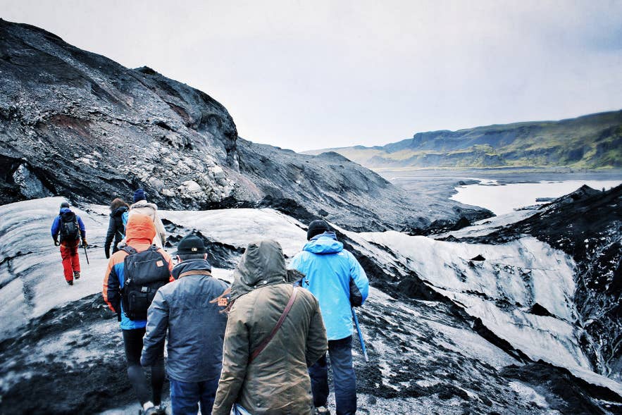 Touristes sur le glacier Solheimajokull montrant quoi porter en Islande pour les randonnées en plein air par temps froid et venteux.