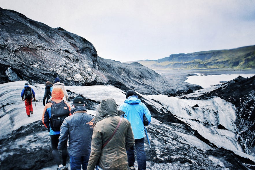 Tourists on Solheimajokull Glacier showing what to wear in Iceland for outdoor hikes in cold, windy conditions. Tourists on Solheimajokull Glacier showing what to wear in Iceland for outdoor hikes in cold, windy conditions.