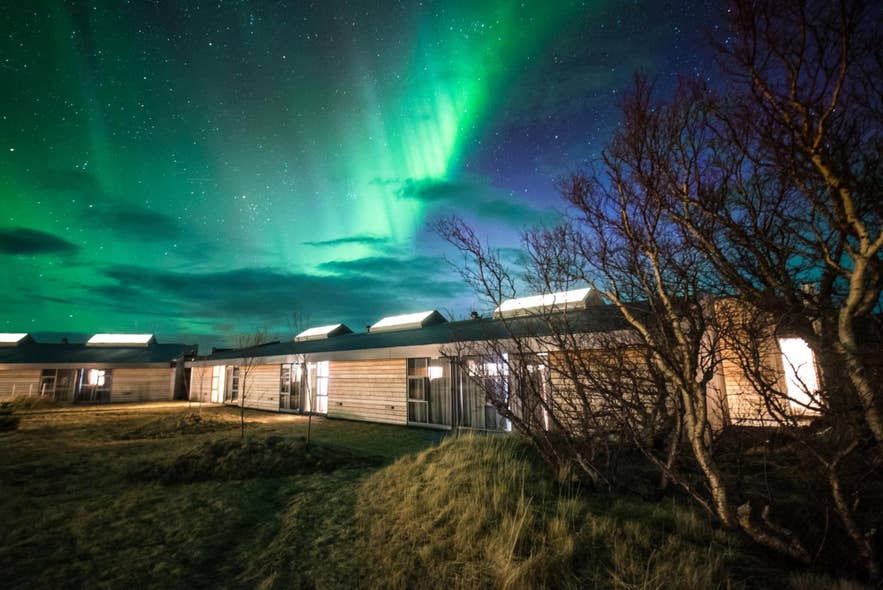 Northern lights in Iceland glowing above Husafell Hotel, a cozy retreat surrounded by nature and starry skies.