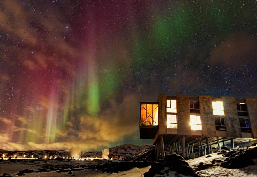 ION Adventure Hotel under northern lights in Iceland with colorful aurora over the mountains.
