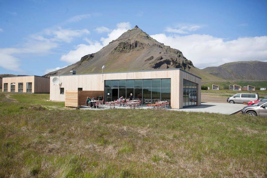A picturesque view of Snjófell Restaurant with a majestic mountain in the background, known for its exceptional cuisine.