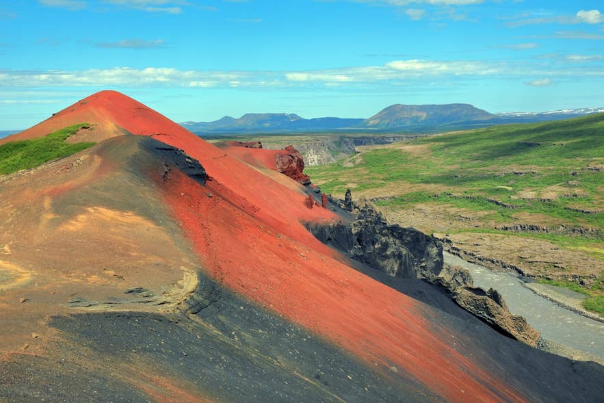Raudholar near Reykjavik is one of the hidden gems in Iceland with vivid red volcanic hills formed by ancient lava flows.