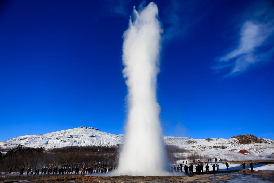 Tourists watch Strokkur erupt under the bright summer sun at the Geysir Geothermal Area in Iceland’s Golden Circle.