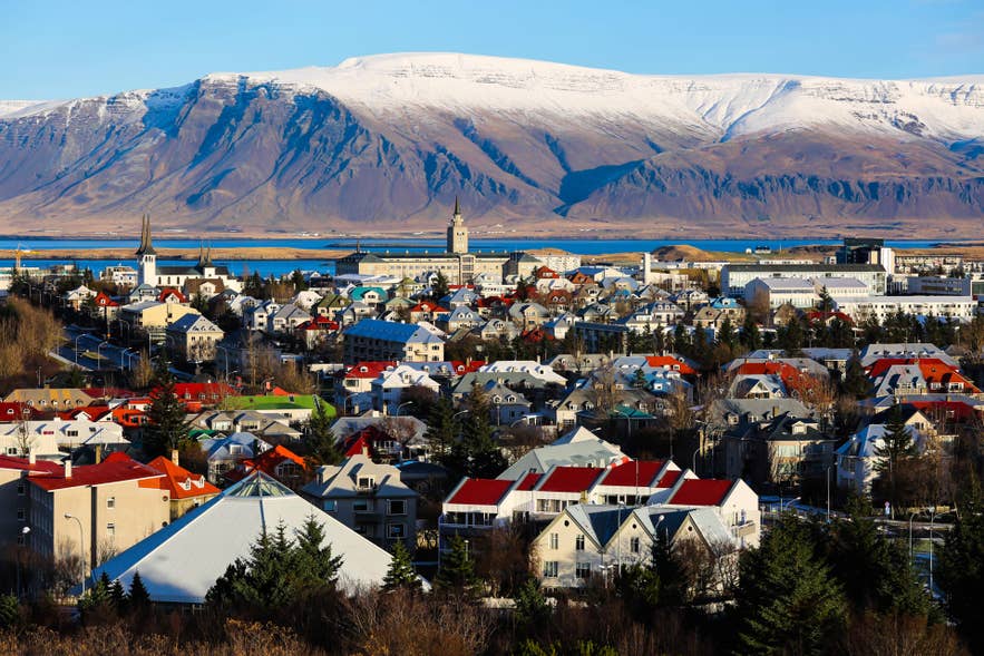 Colorful rooftops of Reykjavik with snowy mountains in the background, one of the best places to stay in Iceland.