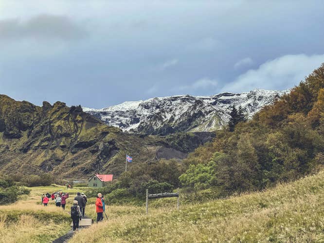 Tourists walking towards mountain huts in Thorsmork with glacier backdrop.
