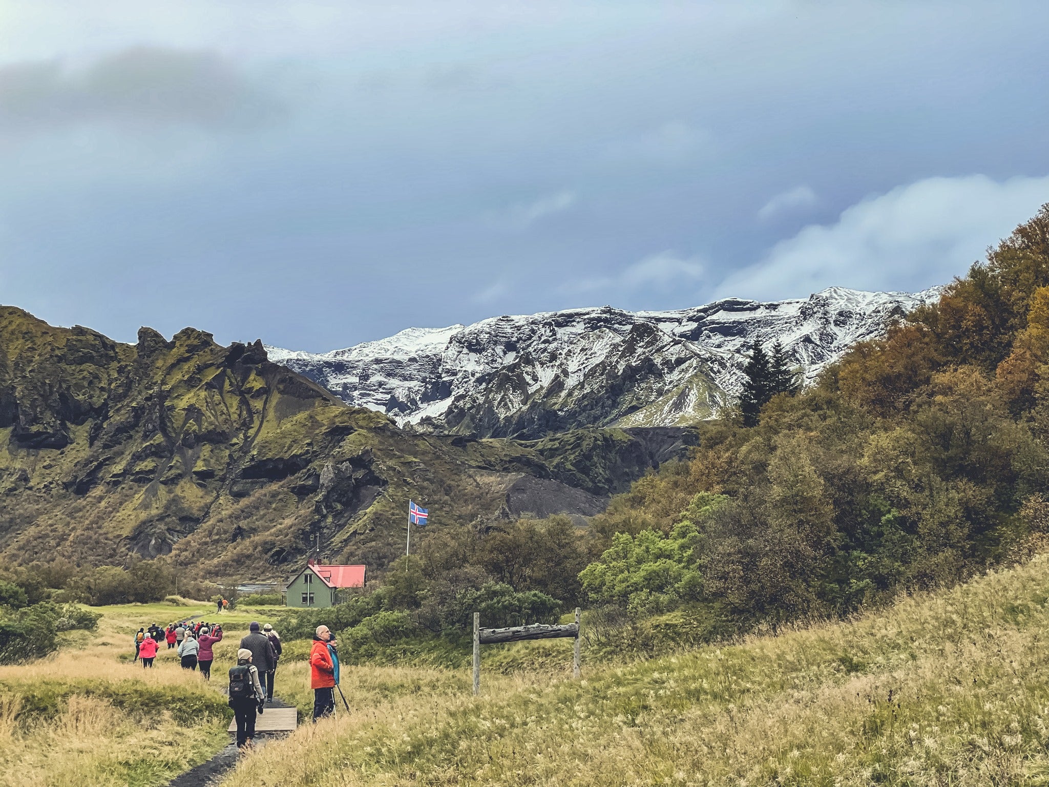 Tourists walking towards mountain huts in Thorsmork with glacier backdrop.