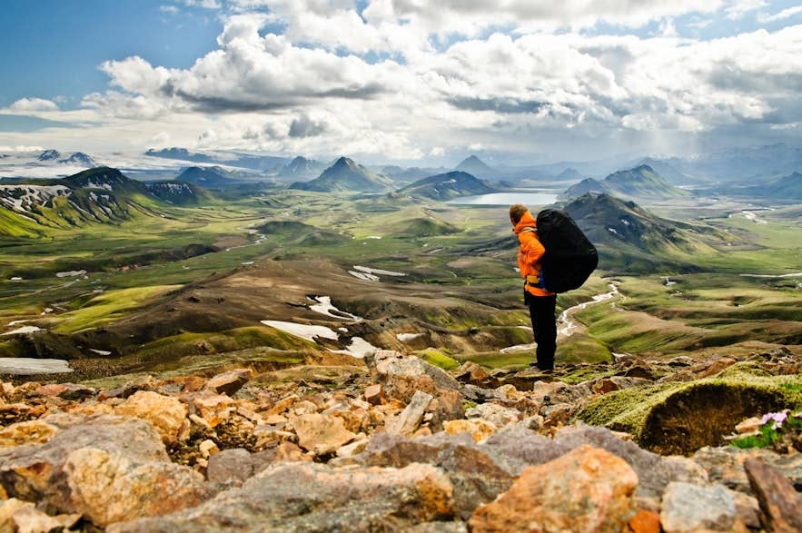 Randonneur au Landmannalaugar montrant quoi porter en Islande pour les treks d’été avec des couches, des bottes et un sac à dos résistant aux intempéries.