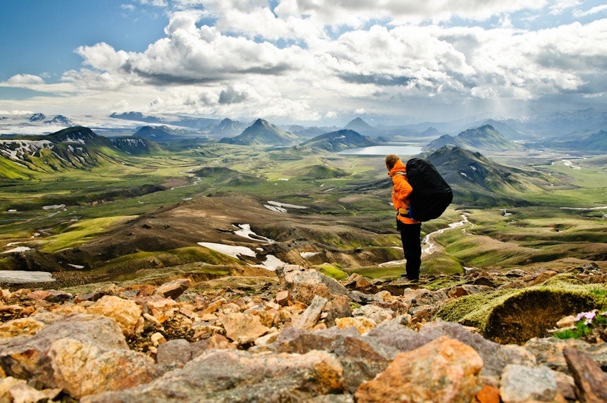 Hiker in Landmannalaugar shows what to wear in Iceland for summer trekking with layers, boots, and a weatherproof backpack.