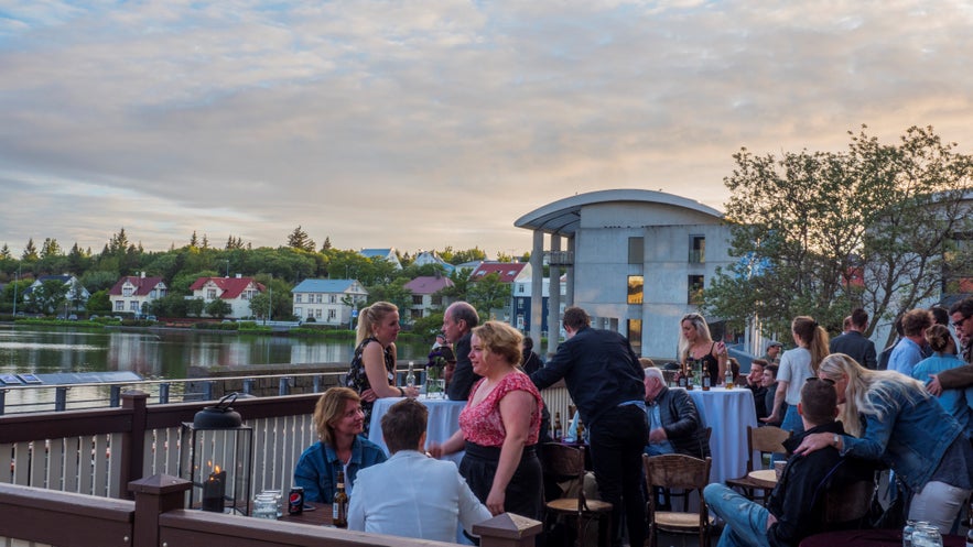 Locals and tourists in summer outfits at a Reykjavik bar show what to wear in Iceland for outdoor dining in warm weather.