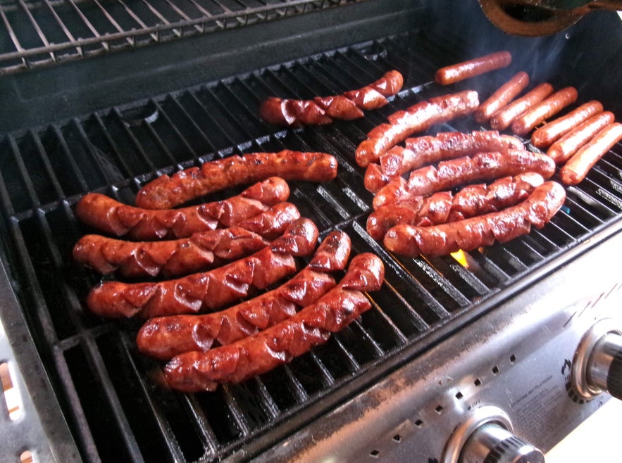 Close-up of grilled sausages and Icelandic hot dog sizzling on a grill.