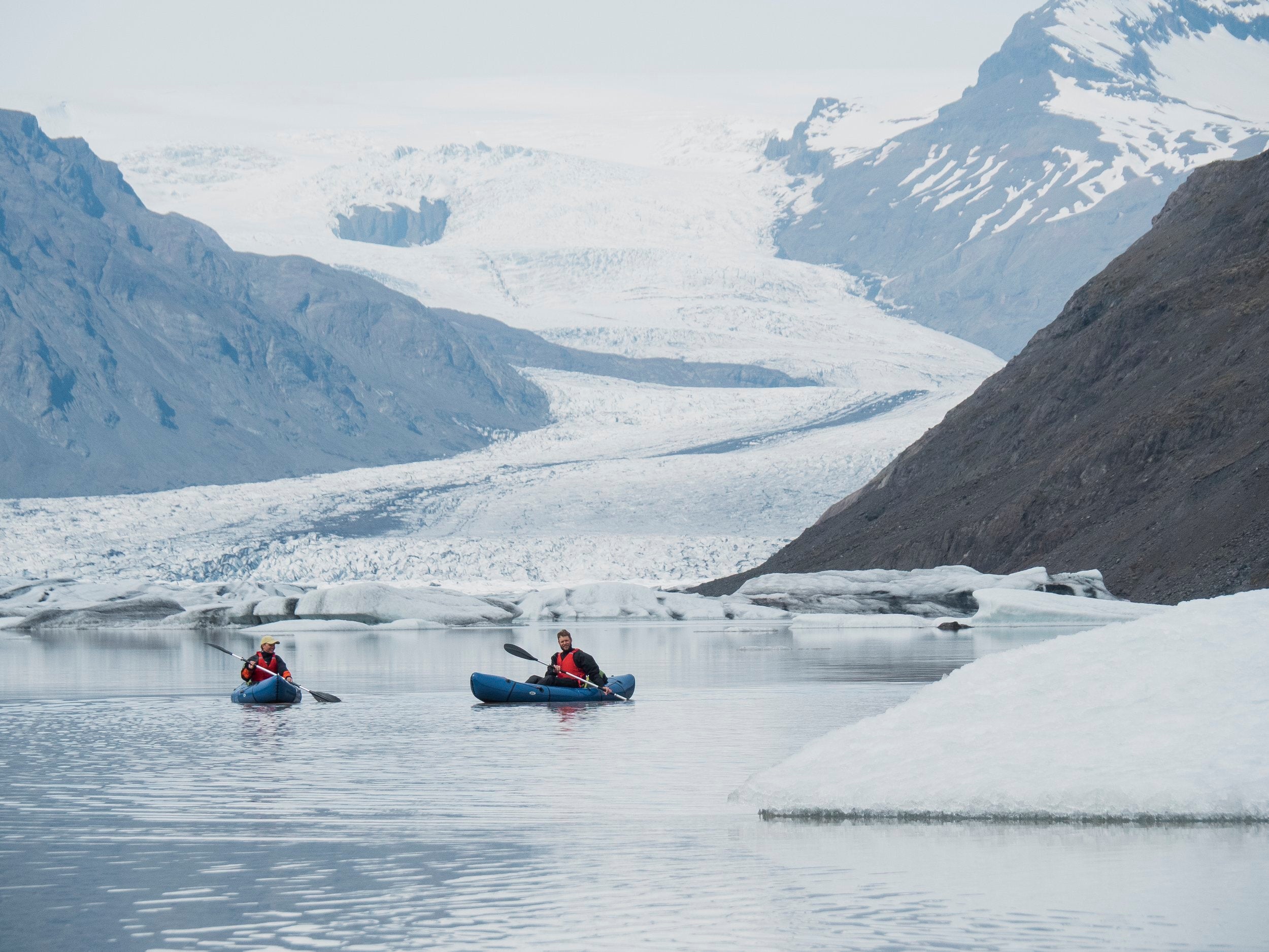 Kayakers exploring floating icebergs and dramatic glacial scenery on Heinabergslon Glacier Lagoon in South Iceland.