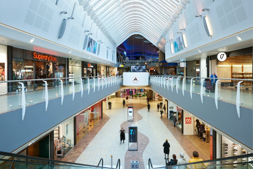 People enjoy shopping in Iceland at Smaralind Mall, with stores, bright lighting, and two floors of shops connected by escalators. People enjoy shopping in Iceland at Smaralind Mall, with stores, bright lighting, and two floors of shops connected by escalators.