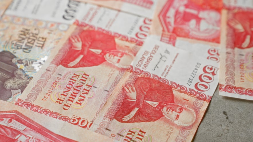 Icelandic krona banknotes in red and white are spread out, showing the portrait design used in the country’s currency. Icelandic krona banknotes in red and white are spread out, showing the portrait design used in the country’s currency.