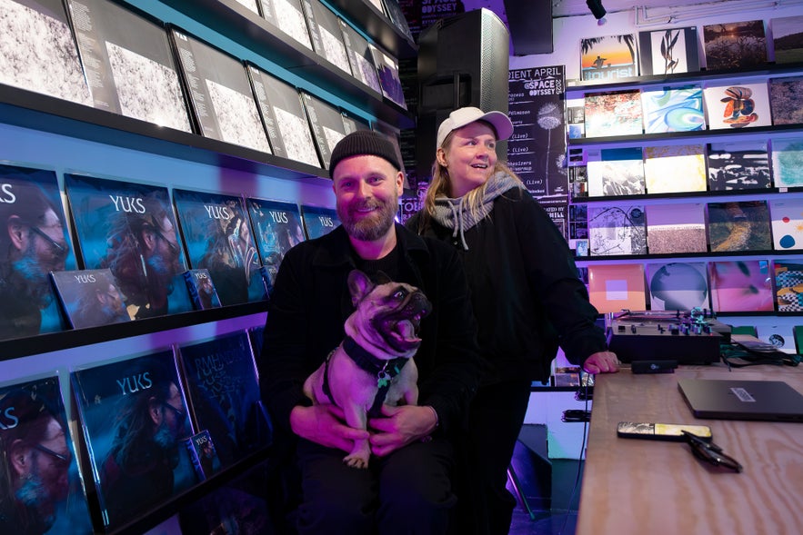 Pan Thorarensen and Guðrún Lárusdóttir with their dog, behind the counter at Space Odyssey in Reykjavík, surrounded by vinyl records.