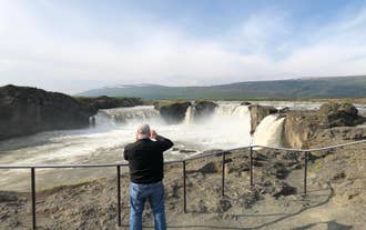 Visitors admiring Godafoss Waterfall in North Iceland.