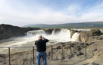 Traveler photographing Godafoss Waterfall in North Iceland during summer.