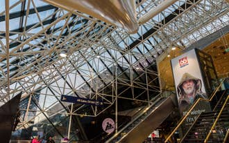 Modern interior of Keflavik International Airport in Iceland with glass ceiling and escalators.