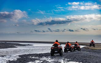 Travelers on an ATV in Skaftafell, Iceland, surrounded by stunning mountain landscapes.