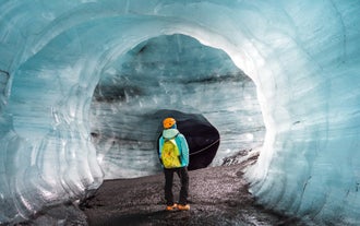 A person examining the ice walls and ceiling of Katla Cave in Iceland.