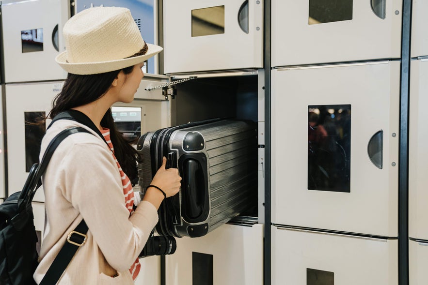 Traveler stores luggage in an airport locker, a practical option for those arriving early in Iceland before hotel check-in.